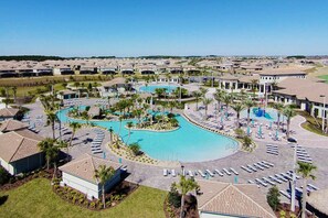 Un resort con piscina central, varias zonas de descanso y un barrio residencial al fondo.