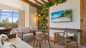 A cozy living area with a sofa, chairs, a small table, and a wall-mounted TV. - Last Minute Disney Getaway! Luxury Villa with Private Pool, Game Room & Themed Bedrooms. Book Now! #151423 (Orlando)
