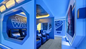 A Star Wars-themed room with a large hexagonal window, blue seating area, and a large screen. - Last Minute Disney Getaway! Luxury Villa with Private Pool, Game Room & Themed Bedrooms. Book Now! #151423 (Orlando)