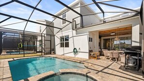 A swimming pool with a glass enclosure, a patio area with outdoor furniture, and a barbecue grill. - Last Minute Disney Getaway! Luxury Villa with Private Pool, Game Room & Themed Bedrooms. Book Now! #151423 (Orlando)