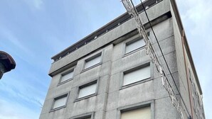 A multi-story building with a flat facade, large windows, and a black entrance with a checkered pattern.