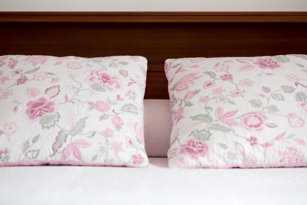 A bed with two pillows featuring a floral pattern.