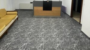A reception area with a marble floor, a reception desk, a sofa, and artwork on the walls.