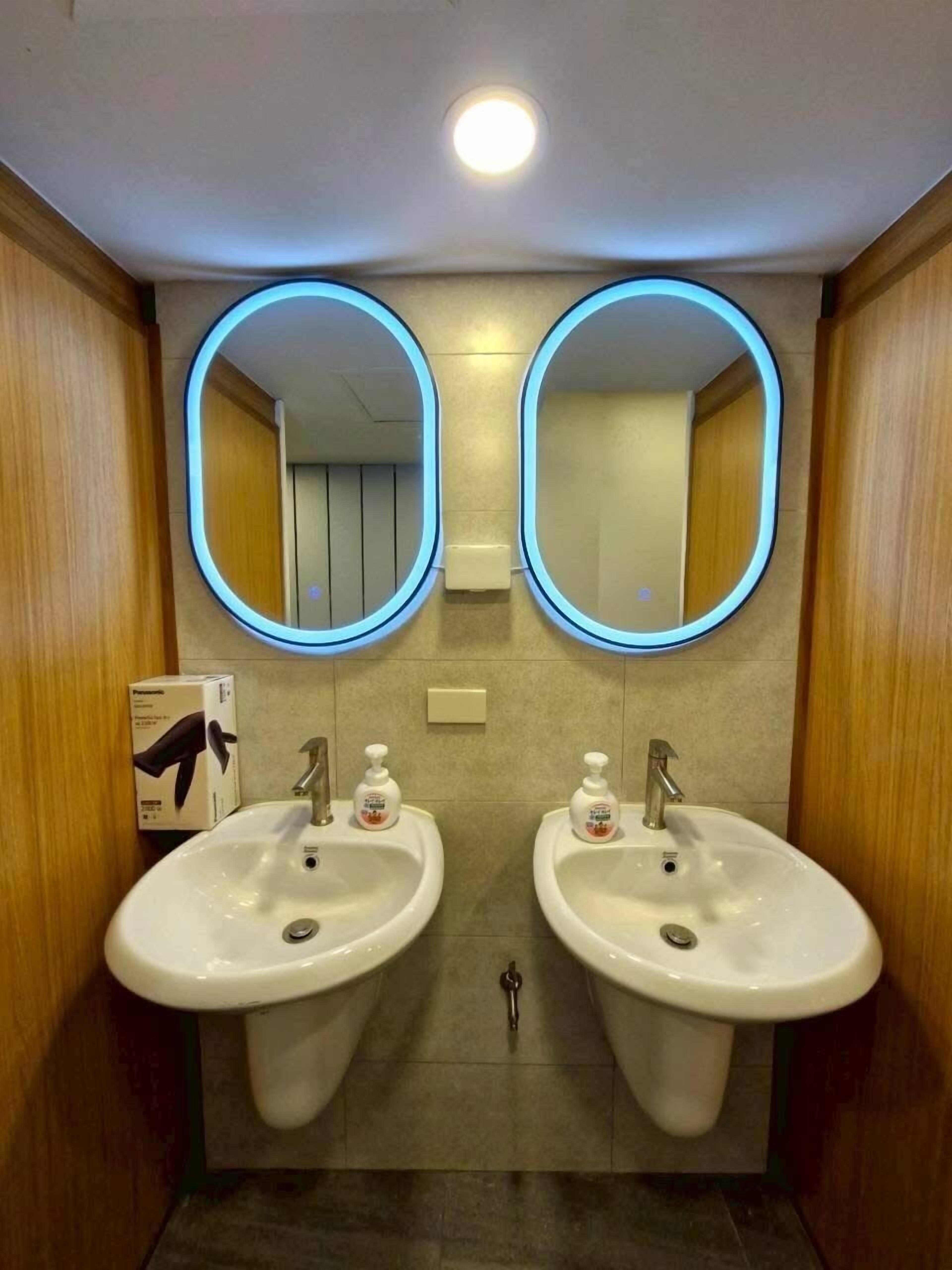A restroom with two sinks, each with a mirror above. There are hand soap dispensers on the sinks.