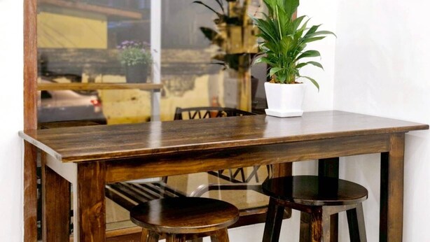 A wooden dining table with two chairs, a potted plant, and a glass partition. - MaMa Hostel  CNX (Chiang Mai)