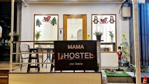 A small hostel named "MAMA HOSTEL" with a wooden facade, a signboard, and a few potted plants. - MaMa Hostel  CNX (Chiang Mai)