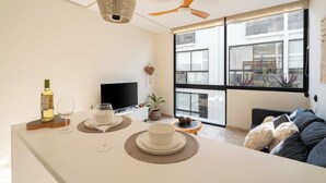Ein modernes Wohnzimmer mit großem Fenster, Deckenventilator und Flachbildfernseher.