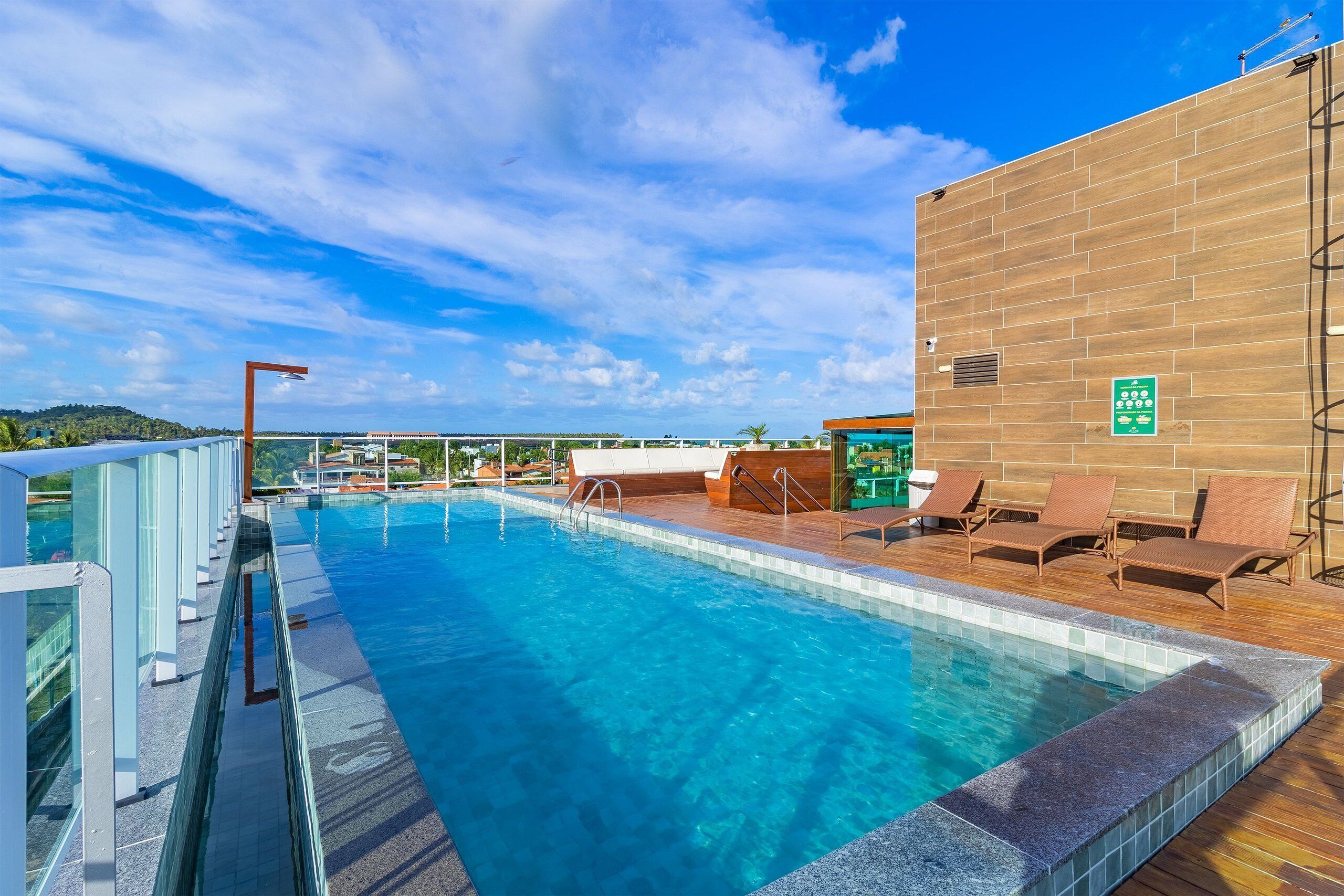 A swimming pool with clear blue water, surrounded by lounge chairs and a wooden deck.