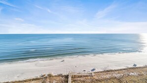 A beach with a clear sky, calm water, and a sandy shore. - Indigo East 1402 (Pensacola)