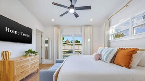 Un dormitorio con cama, mesita de noche y un ventanal grande.