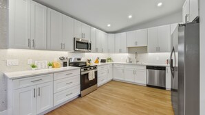 Una cocina moderna con armarios blancos, electrodomésticos de acero inoxidable y piso de madera.
