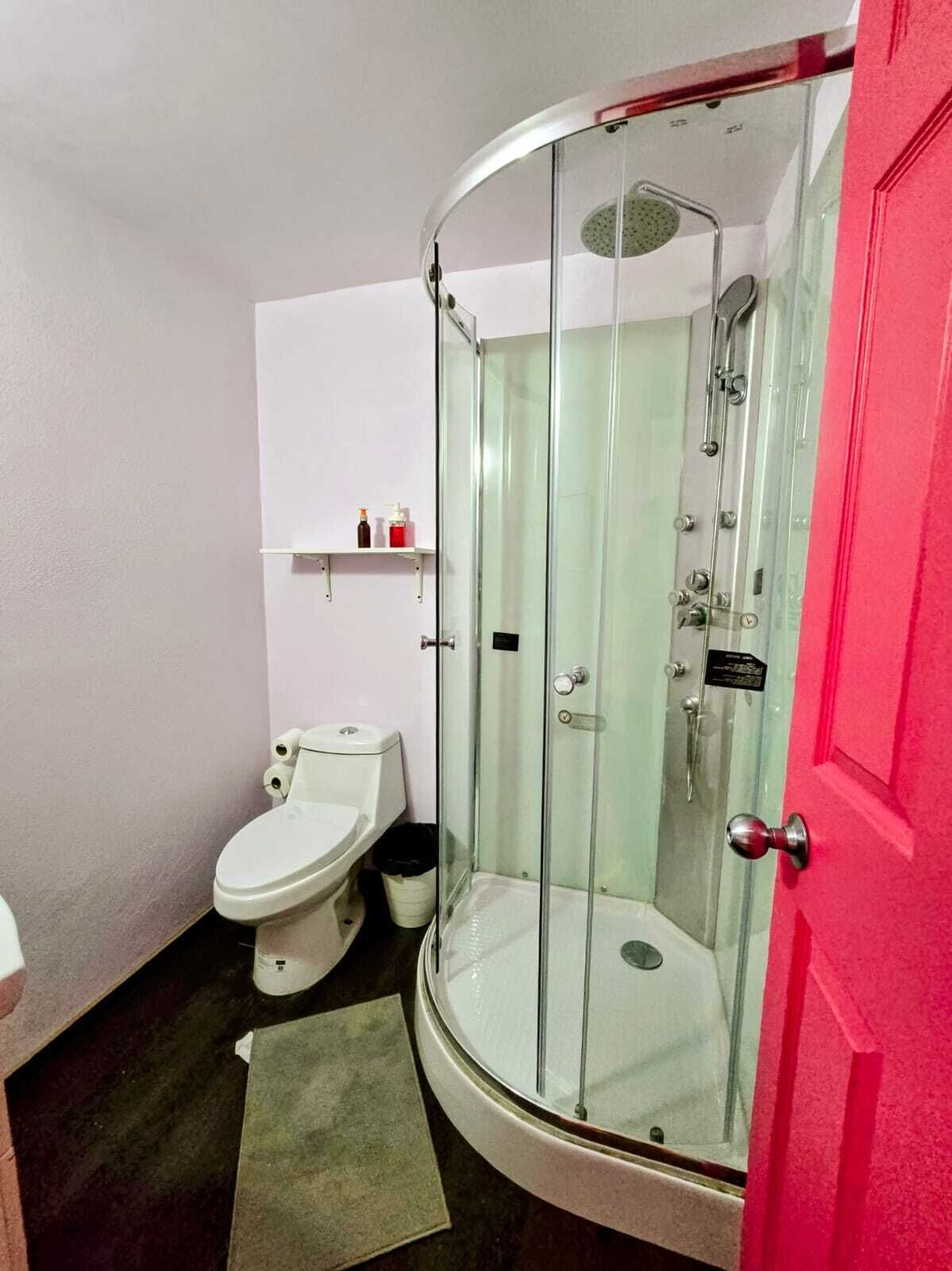 Une salle de bain avec une douche à parois de verre, des toilettes et un lavabo.