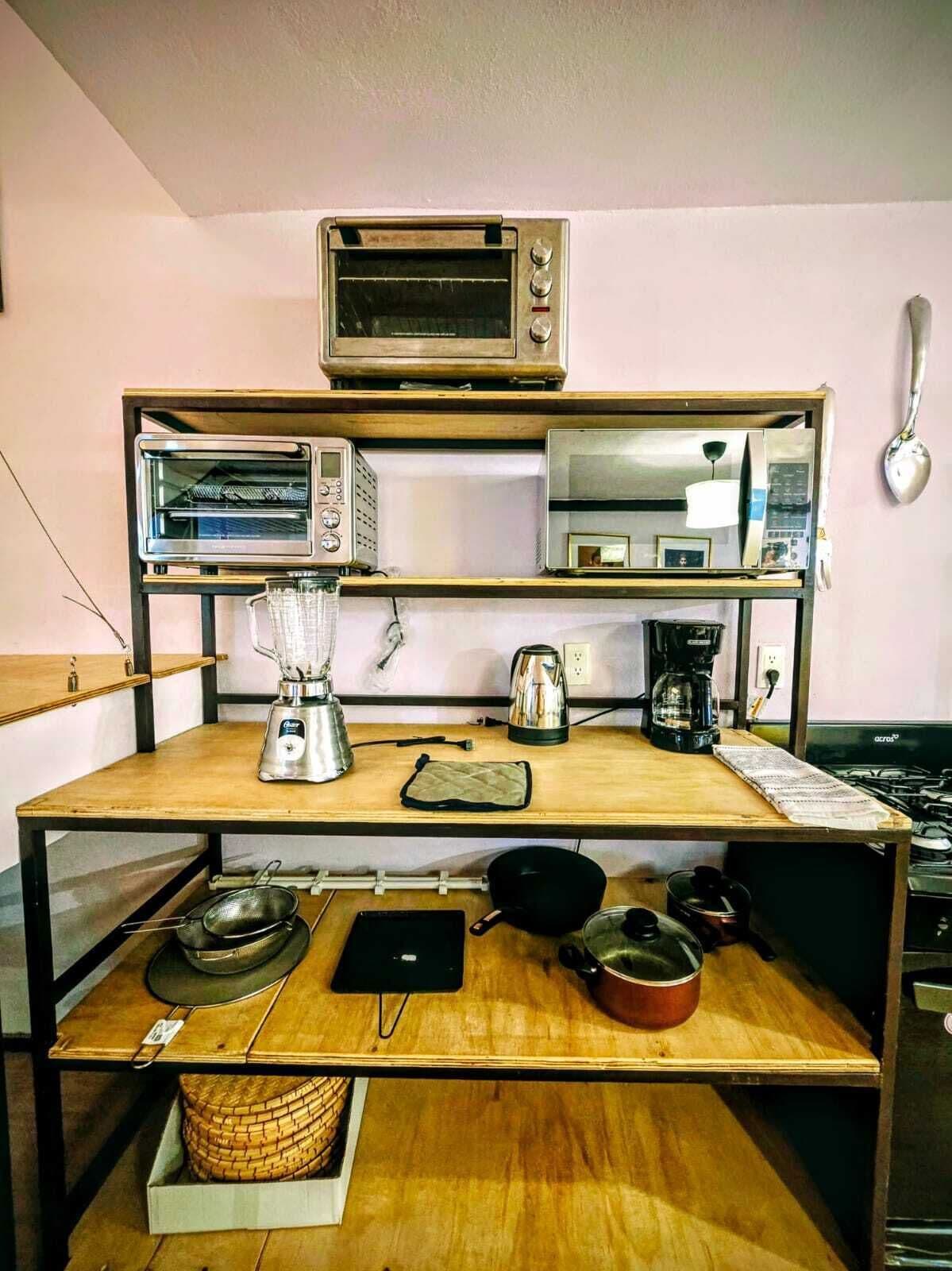 A kitchen with a microwave, toaster, and coffee maker on a wooden shelf.