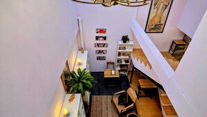 A modern loft-style apartment with a central staircase, a dining area, and a living space with a chandelier. - CAXA TEGUI (Mexico City)