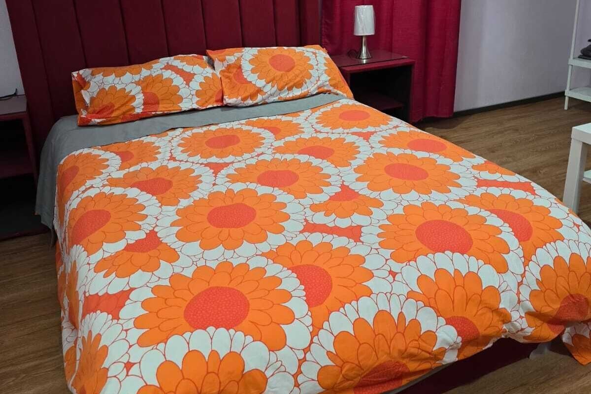 A bedroom with a bed, a nightstand, and a red curtain.