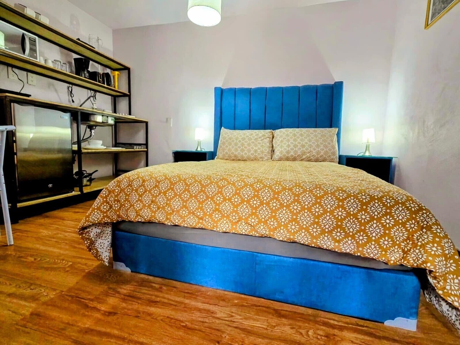 Une chambre à coucher comprenant un lit, une table de chevet, une commode et un réfrigérateur.