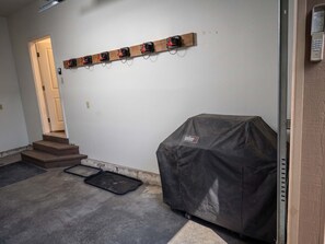 Un garaje con un banco de madera, una parrilla cubierta y un estante para herramientas en la pared.