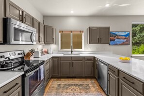 A modern kitchen with stainless steel appliances, a large window, and a view of a river. - Big Sky Townhome | Fireplace + Hot Tub (Big Sky)