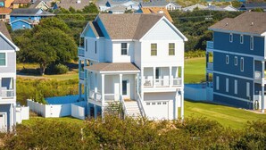 A two-story house with a front porch and a small staircase leading to the entrance. - Ocean-view 4-bedroom, 3.5 bath Corrolla home w/pool+hot tub - sleeps 11 (Corolla)