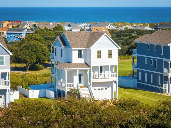 A two-story house with a front porch and a small staircase leading to the entrance. - Ocean-view 4-bedroom, 3.5 bath Corrolla home w/pool+hot tub - sleeps 11 (Corolla)