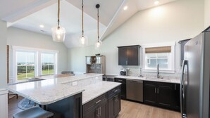 A spacious kitchen with a large island, dark cabinetry, and stainless steel appliances. - Ocean-view 4-bedroom, 3.5 bath Corrolla home w/pool+hot tub - sleeps 11 (Corolla)
