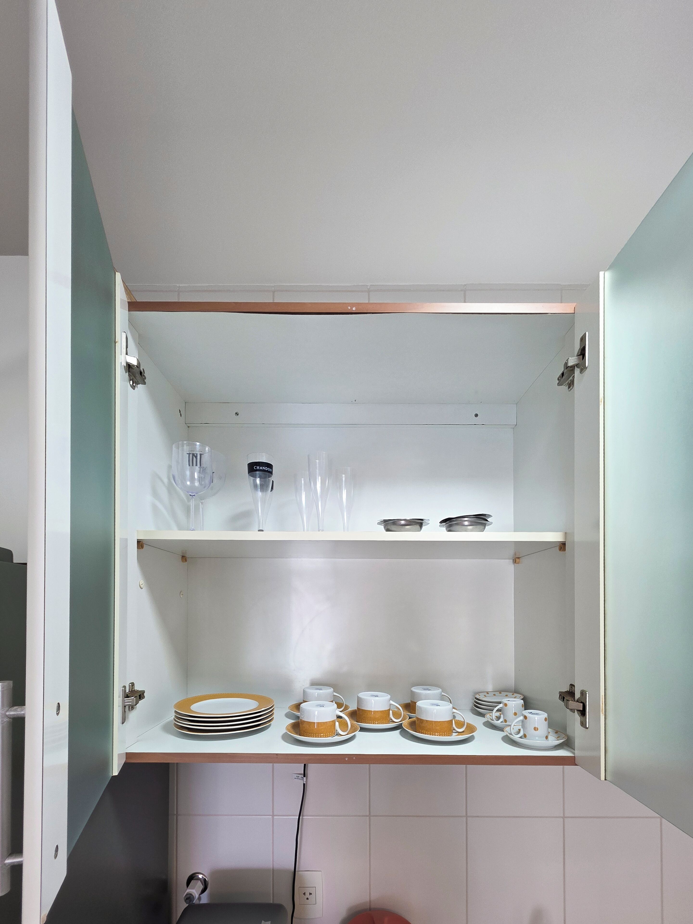 Cocina con armarios abiertos que exhiben vajilla, vasos y utensilios.