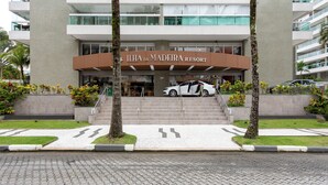 Entrada de un hotel con un coche estacionado adelante, escalones que conducen a la entrada y un letrero que dice "Ilha da Madeira Resort".