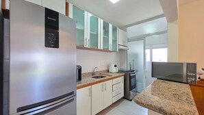 Una cocina moderna con electrodomésticos de acero inoxidable, armarios blancos y encimeras de granito.