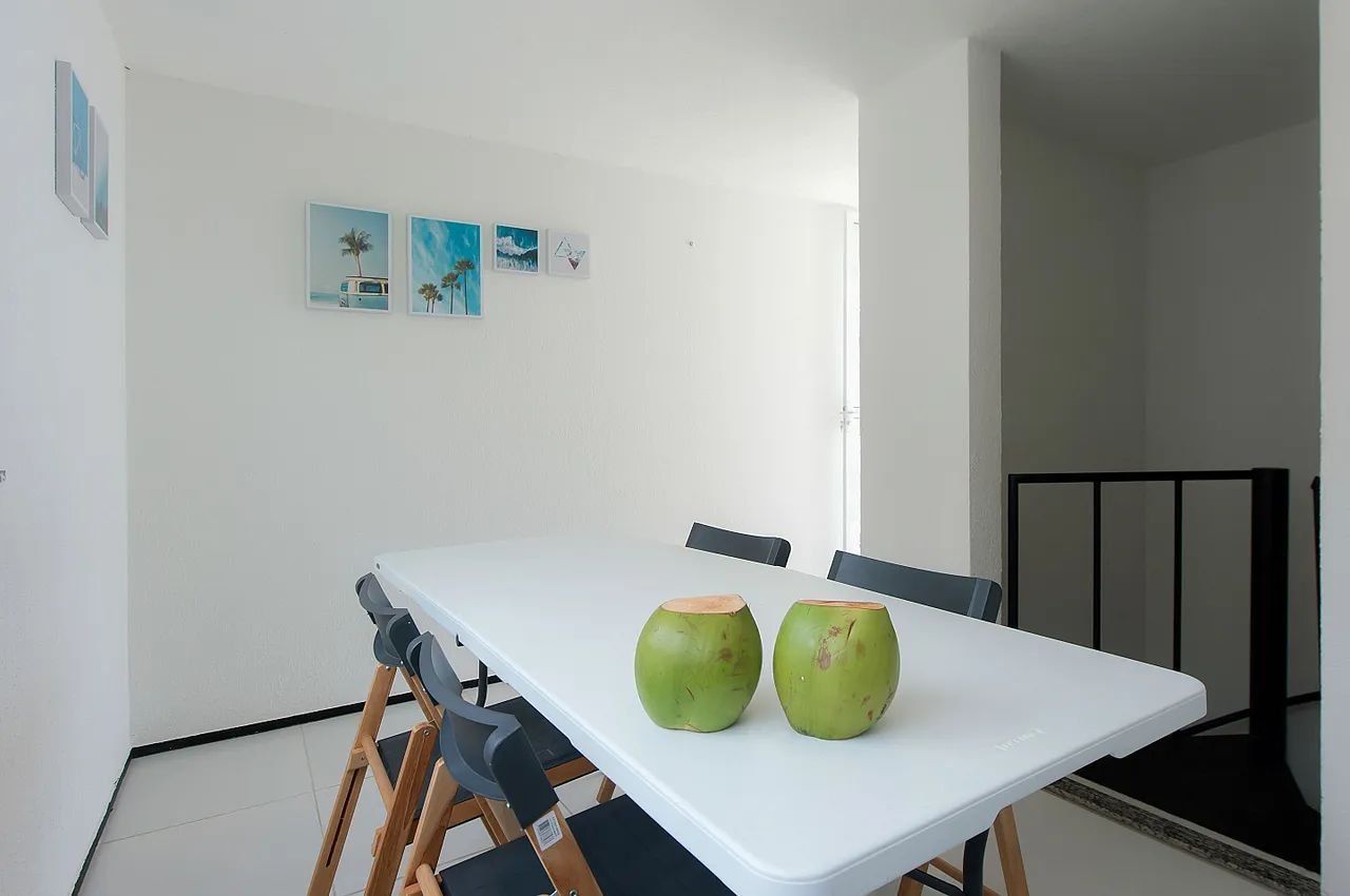 A dining area with a white table, two green vases, and black chairs.