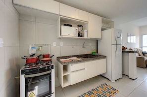 A compact kitchen with white cabinets, a built-in oven, a microwave, and a refrigerator. - Beach Townhouses Triplex Near the Beach By Carpediem (Aquiraz)