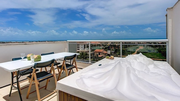 Ein Balkon mit Tisch und Stühlen, Blick aufs Meer und eine Glastrennwand.