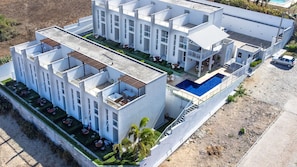 A modern hotel with multiple balconies, a swimming pool, and outdoor seating areas. - Beach Townhouses Triplex Near the Beach By Carpediem (Aquiraz)