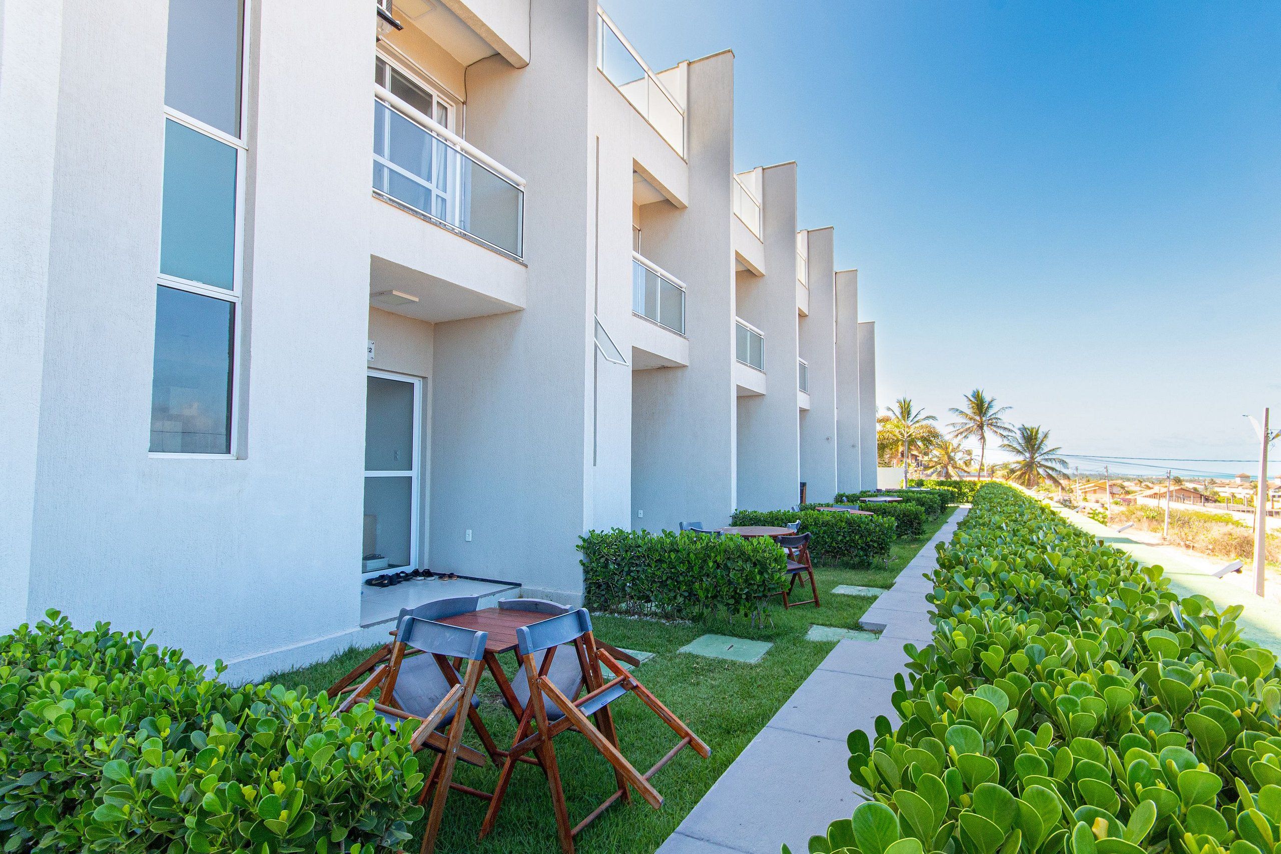 A modern hotel with a pool area, outdoor seating, and a view of the ocean.