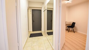 Un couloir avec deux portes, un bureau avec une chaise et un luminaire au plafond.