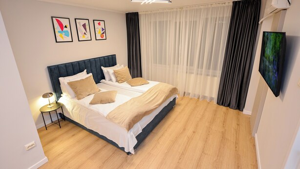 Une chambre à coucher moderne avec un grand lit, une table de chevet et un téléviseur fixé au mur.