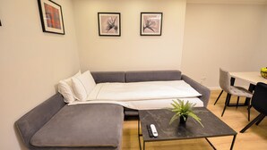 Un salon moderne avec un canapé gris, une petite table basse agrémentée d’une plante, et un coin repas comprenant une table et des chaises.