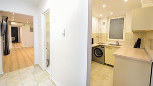 Une petite cuisine équipée d’un lave-linge, d’un évier et d’une fenêtre.