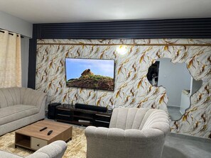 Un salon moderne doté d’un grand téléviseur à écran plat, d’un canapé, d’une table basse et d’une cheminée.