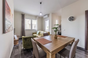 Una sala moderna con una mesa de comedor de madera, sillones verdes, un sofá amarillo y una planta en maceta.