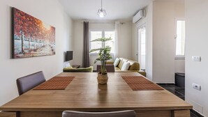 Un salon moderne avec une table à manger en bois, un canapé et une grande fenêtre.