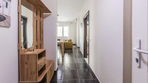 Un couloir étroit avec une coiffeuse en bois, un canapé jaune et une porte dotée d’une poignée.