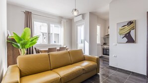 Un salon moderne avec un canapé en cuir, un coin repas et une cuisine en arrière-plan.