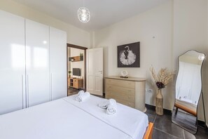 A modern hotel room with a large bed, a wooden dresser, a flat-screen TV, a mirror, and a painting on the wall.