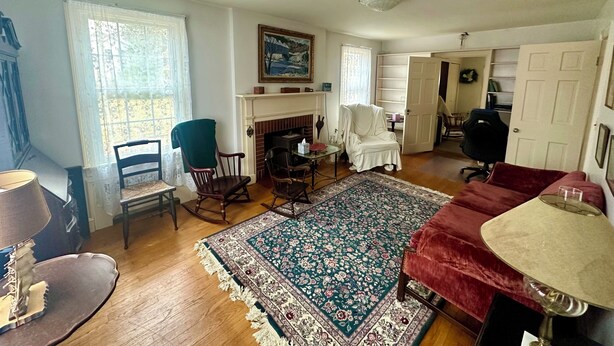 A living room with a fireplace, a rocking chair, a red sofa, and a dining table with chairs.