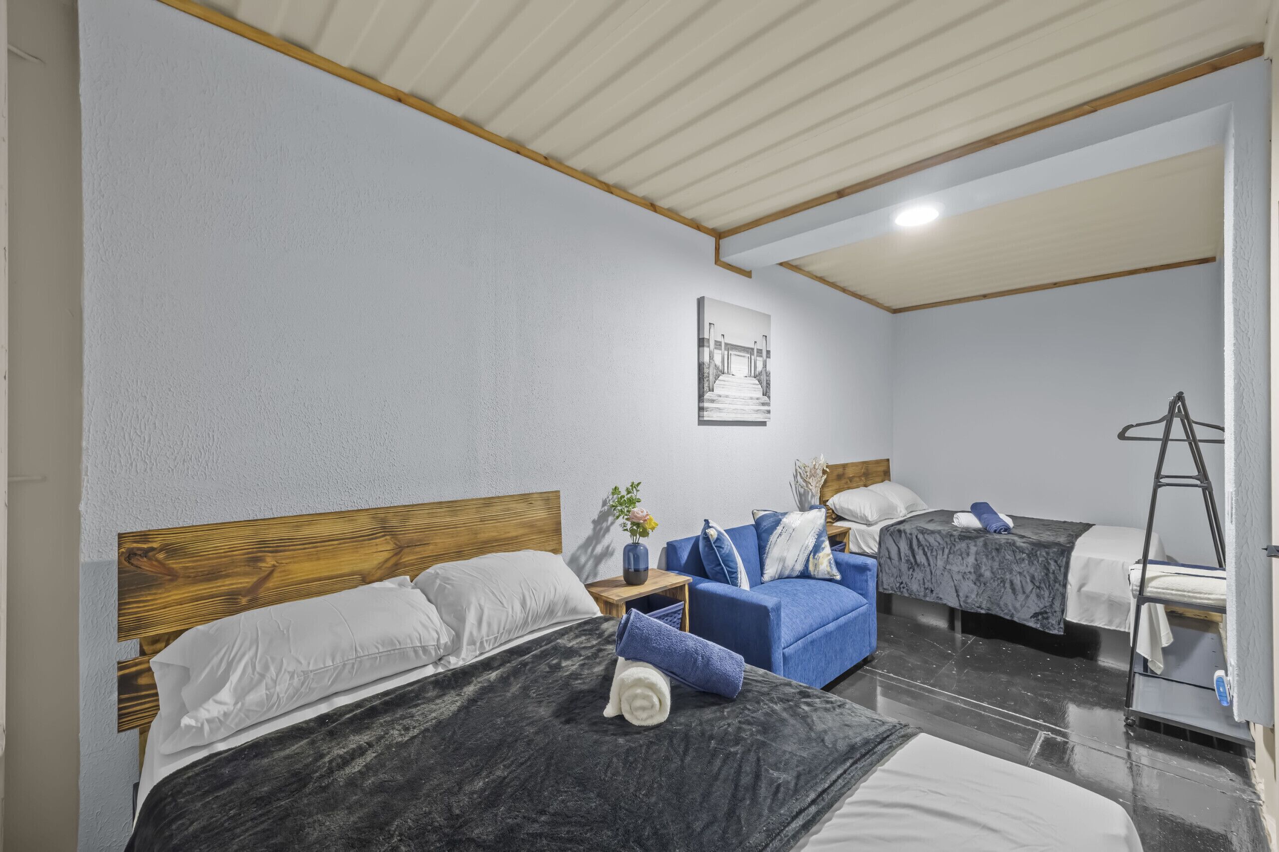 A hotel room with two beds, a sofa, a ladder, and a framed picture on the wall.