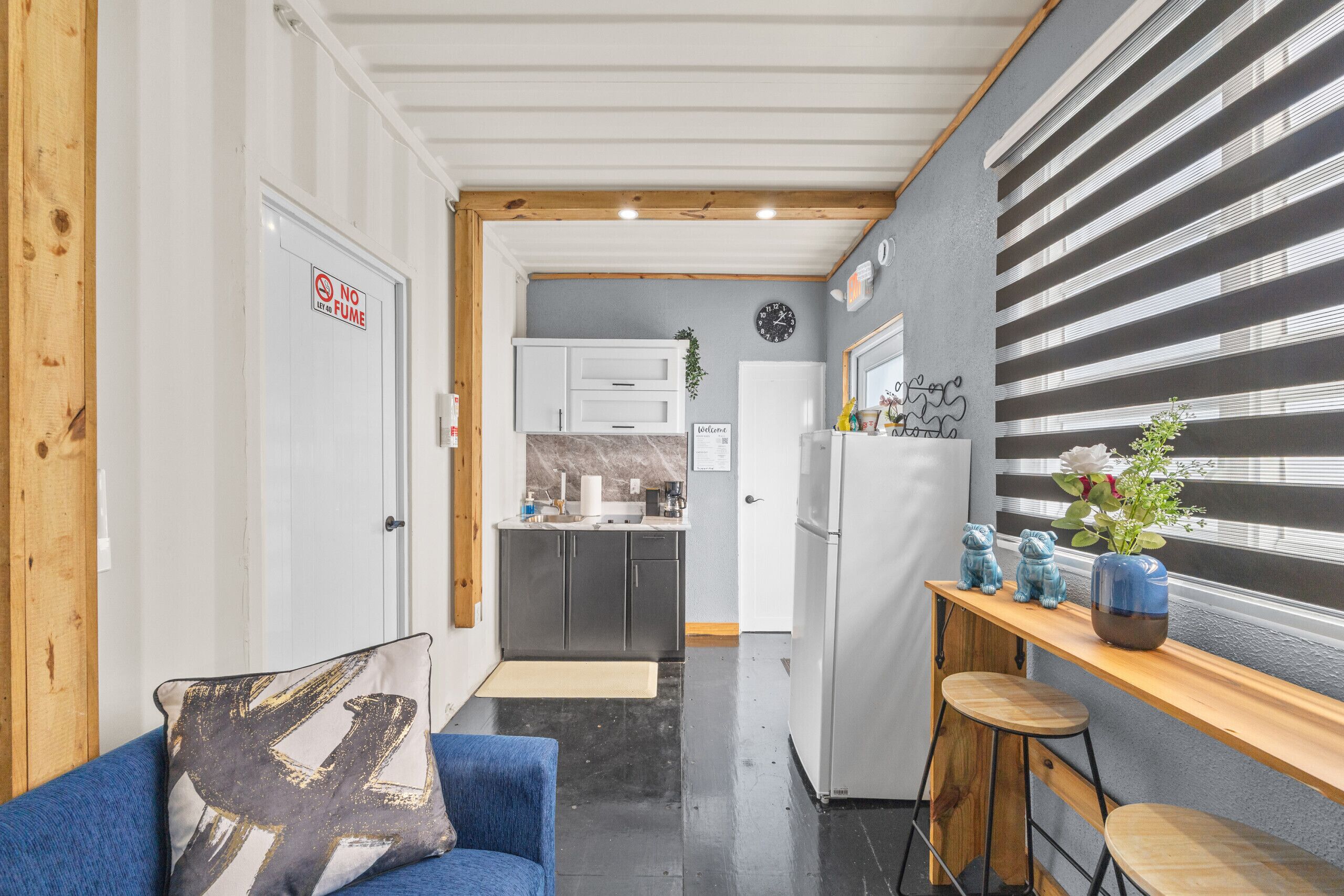 A compact kitchen with white cabinets, a white refrigerator, and a wooden bar area with stools.