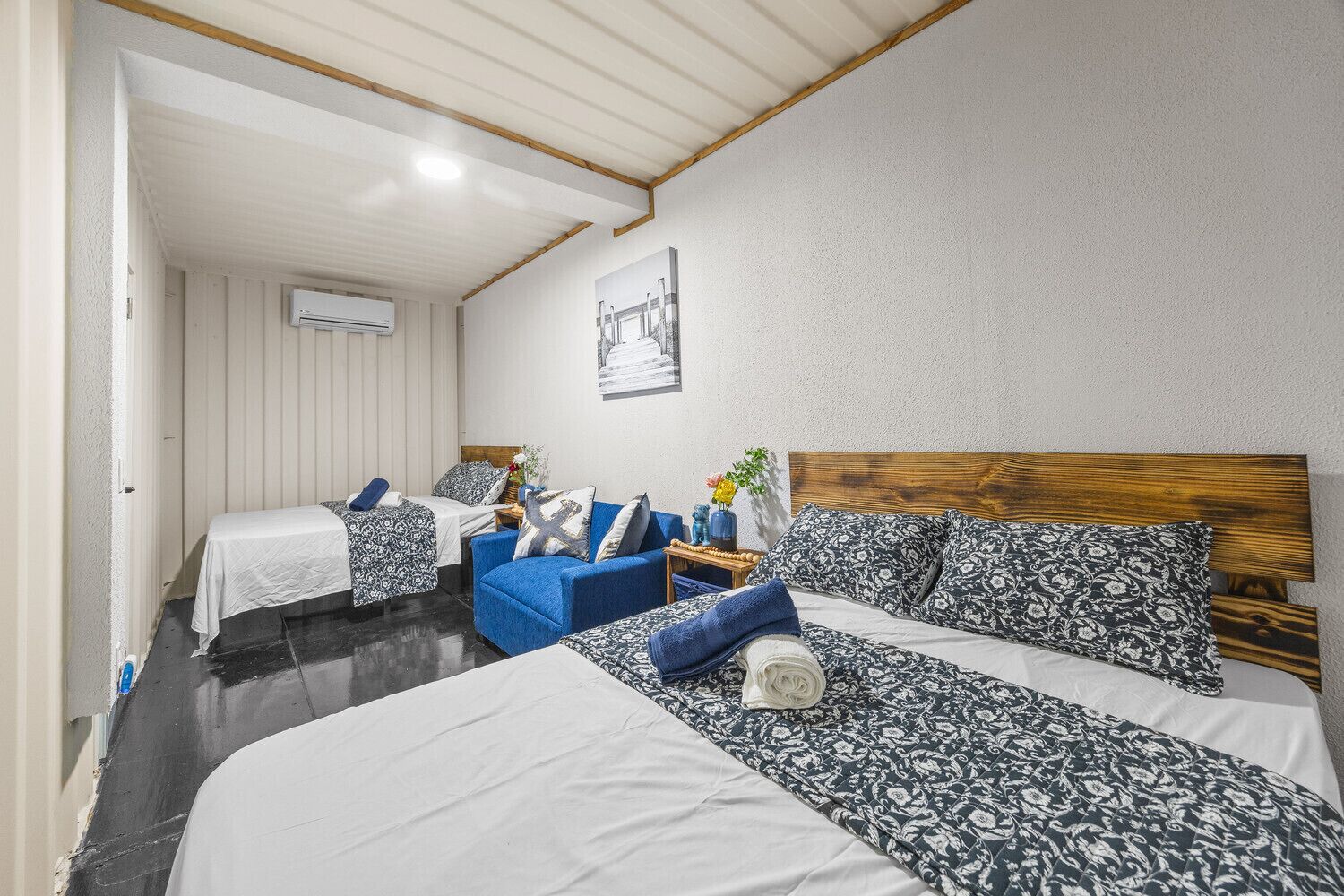 Une chambre avec deux lits, un canapé bleu et une tête de lit en bois.