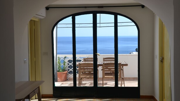 A room with a view of the sea through a large arched window. - Spacious 5-bedroom in Positano center, on 2 floor,2 terraces overlooking the sea (Positano)