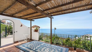 A terrace with a tiled table and chairs, a view of the sea, and a thatched roof. - Spacious 5-bedroom in Positano center, on 2 floor,2 terraces overlooking the sea (Positano)