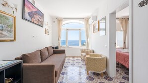 A room with a sofa, armchairs, a small table, and a bed with a pink bedspread. - Spacious 5-bedroom in Positano center, on 2 floor,2 terraces overlooking the sea (Positano)